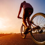 Asian,Men,Are,Cycling,Road,Bike,In,The,The,Sunset