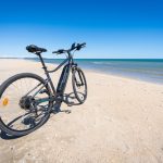 An,Electric,Bicycle,On,A,White,Sand,Beach,With,A
